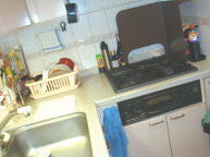 シンクとガス台。食器かごや調味料ラックなどが置いてあり、調理スペースがかなり狭いです。