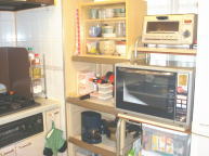 キッチンの窓際側。冷蔵庫、オーブンレンジ、その他電化製品、ミニ食器棚などあります。